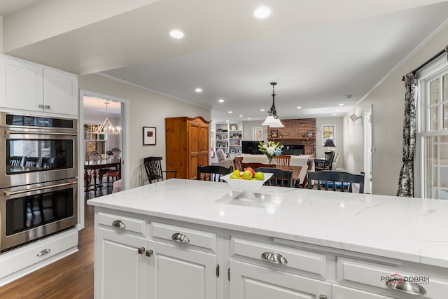 kitchen featuring white cabinets, a kitchen breakfast bar, stainless steel double oven, and a fireplace