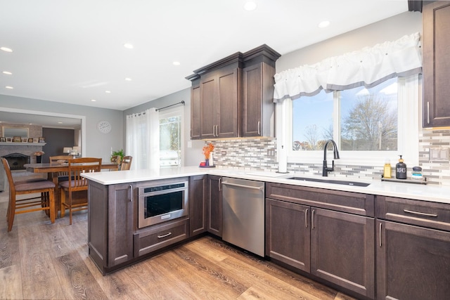 kitchen with tasteful backsplash, wood-type flooring, sink, kitchen peninsula, and stainless steel appliances