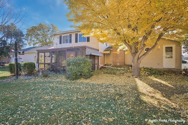 view of front of house with a front yard and a sunroom