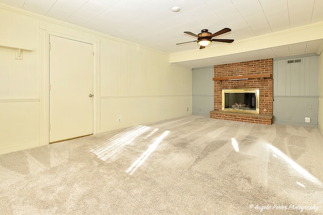 unfurnished living room with ceiling fan, crown molding, carpet floors, and a fireplace