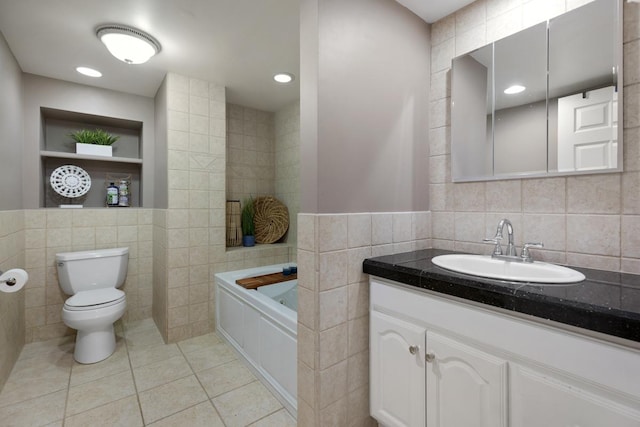 bathroom featuring a washtub, toilet, vanity, tile patterned floors, and tile walls