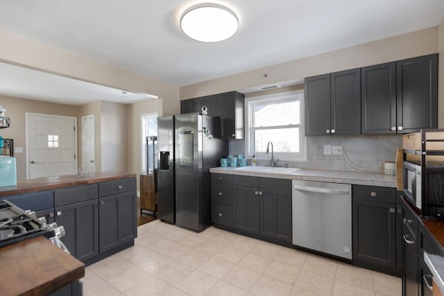 kitchen with sink, butcher block countertops, backsplash, and appliances with stainless steel finishes