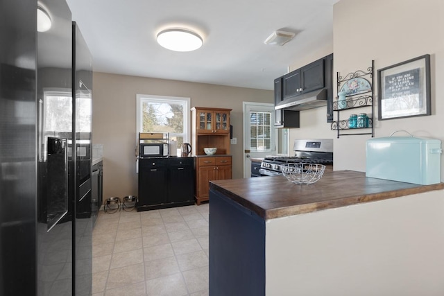 kitchen with wooden counters, black refrigerator with ice dispenser, and stainless steel gas range oven