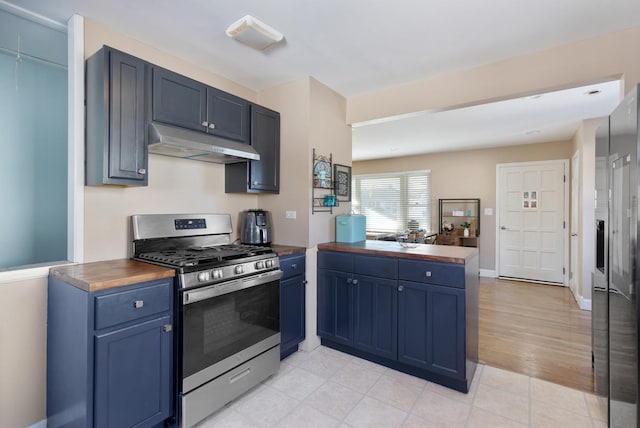 kitchen with blue cabinets, stainless steel appliances, kitchen peninsula, and wood counters