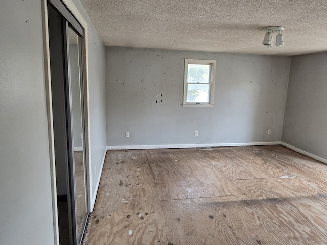 unfurnished room with wood-type flooring and a textured ceiling