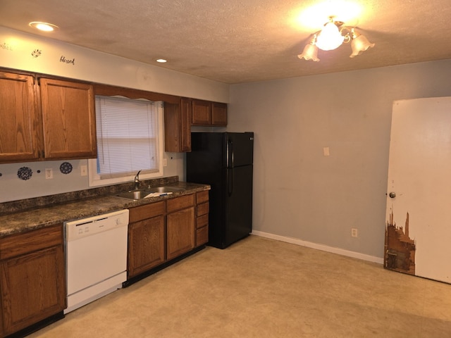 kitchen featuring white dishwasher, black refrigerator, sink, and a textured ceiling