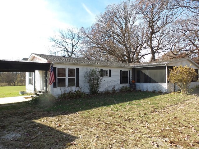 rear view of house featuring a sunroom and a lawn