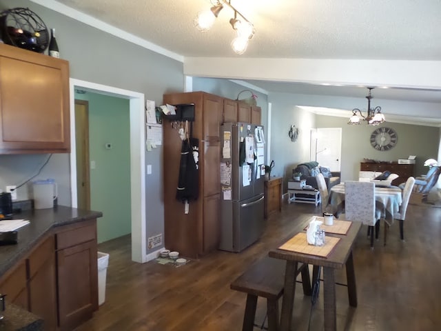 dining room featuring dark wood-type flooring, a chandelier, a textured ceiling, and vaulted ceiling