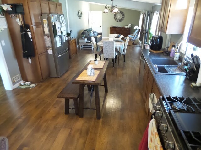 kitchen featuring dark hardwood / wood-style flooring, hanging light fixtures, sink, and stainless steel appliances