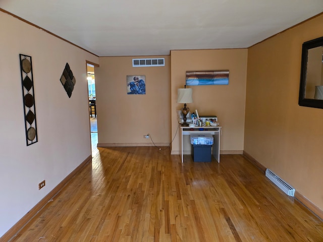 empty room with baseboard heating and light hardwood / wood-style floors