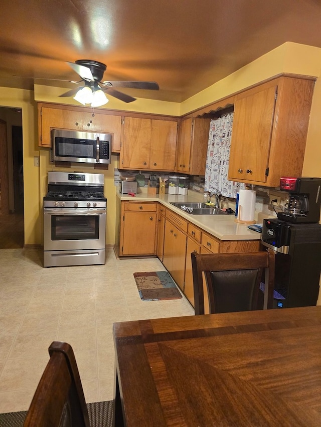 kitchen featuring sink, appliances with stainless steel finishes, tasteful backsplash, ceiling fan, and light tile patterned floors