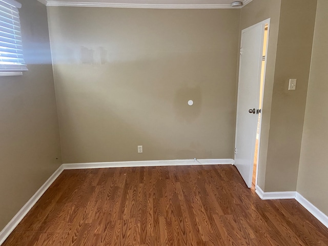 empty room with dark hardwood / wood-style floors and crown molding