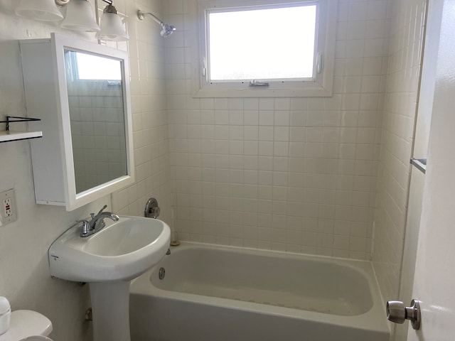 bathroom with tiled shower / bath, a healthy amount of sunlight, and toilet