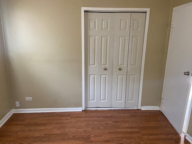 unfurnished bedroom featuring dark hardwood / wood-style flooring and a closet