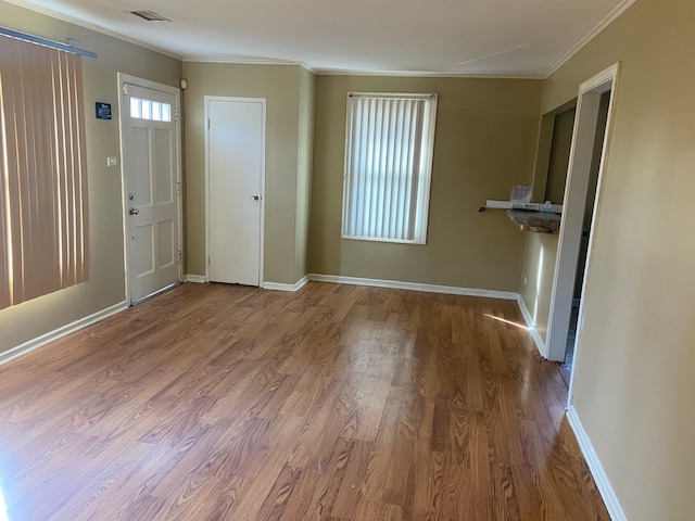 foyer with wood-type flooring and crown molding