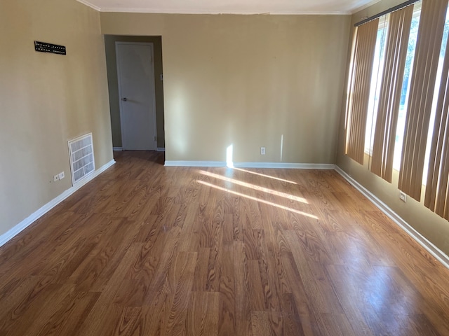 empty room with hardwood / wood-style floors and crown molding