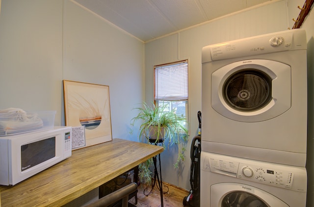 washroom with stacked washer and dryer and wood-type flooring