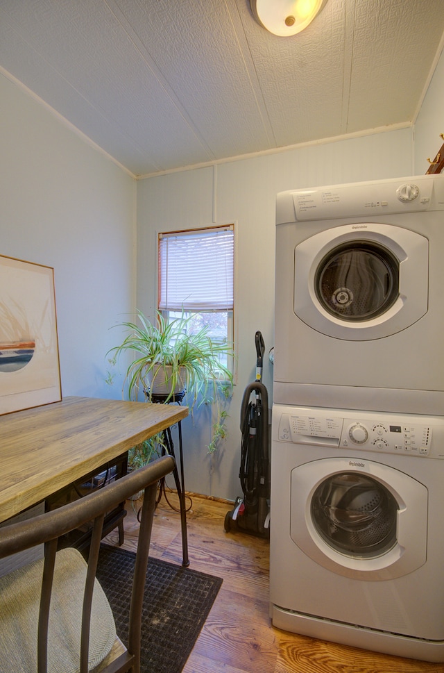 washroom featuring ornamental molding, a textured ceiling, hardwood / wood-style flooring, and stacked washer and clothes dryer