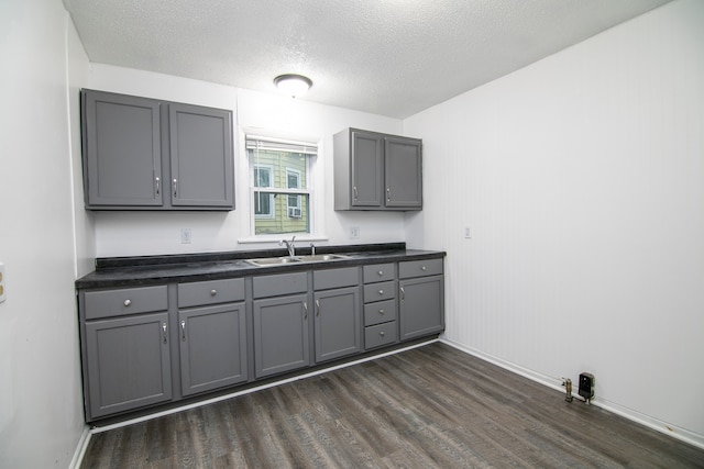 kitchen with gray cabinetry, sink, a textured ceiling, and dark hardwood / wood-style flooring