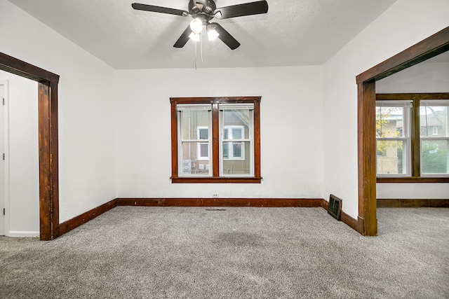 carpeted empty room featuring ceiling fan and a textured ceiling