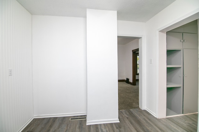 corridor with dark wood-type flooring and a textured ceiling