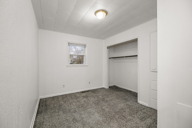 unfurnished bedroom with a closet and dark colored carpet