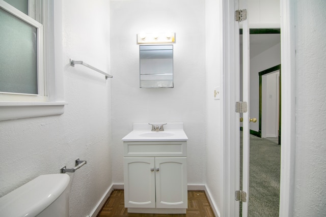 bathroom featuring toilet, vanity, and parquet floors