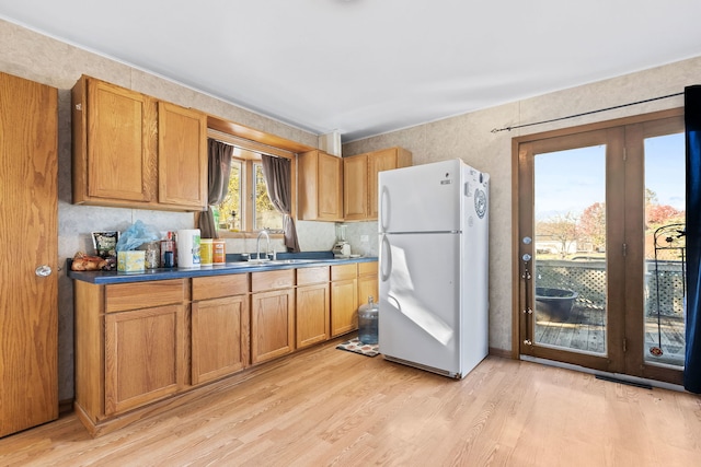 kitchen with light wood-type flooring, sink, and white refrigerator