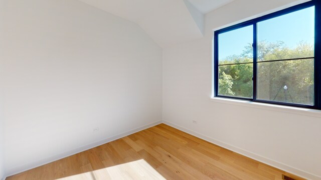 unfurnished room featuring hardwood / wood-style flooring, a healthy amount of sunlight, and lofted ceiling