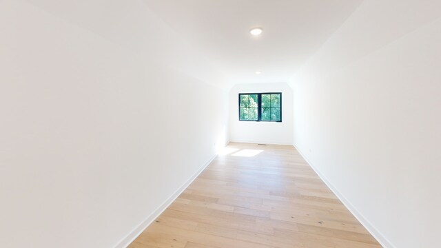 hallway with light hardwood / wood-style floors and vaulted ceiling