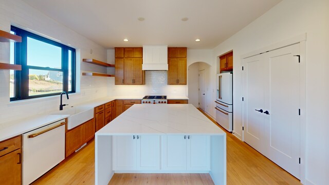 kitchen with white appliances, light hardwood / wood-style floors, a kitchen island, and tasteful backsplash