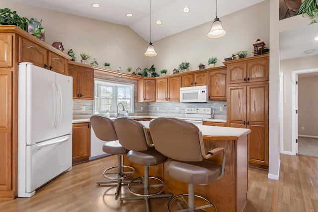 kitchen featuring decorative backsplash, white appliances, light hardwood / wood-style floors, a kitchen island, and hanging light fixtures