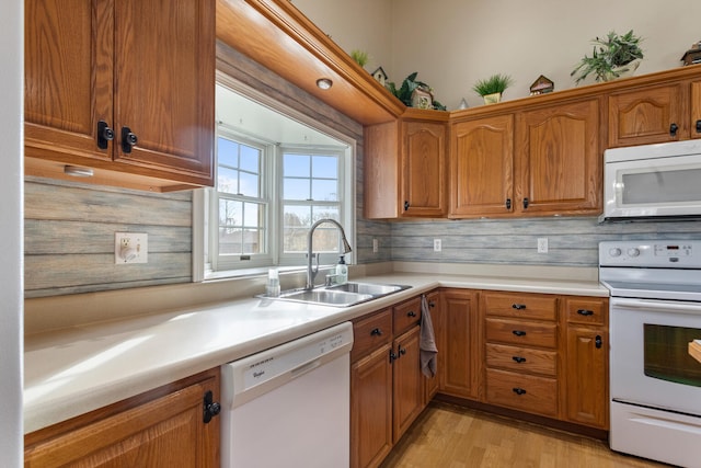 kitchen featuring decorative backsplash, light wood-type flooring, white appliances, and sink