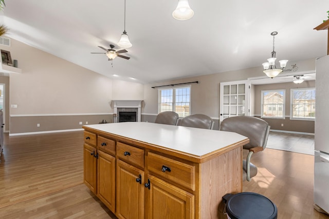 kitchen featuring light hardwood / wood-style flooring, a kitchen island, hanging light fixtures, and ceiling fan with notable chandelier