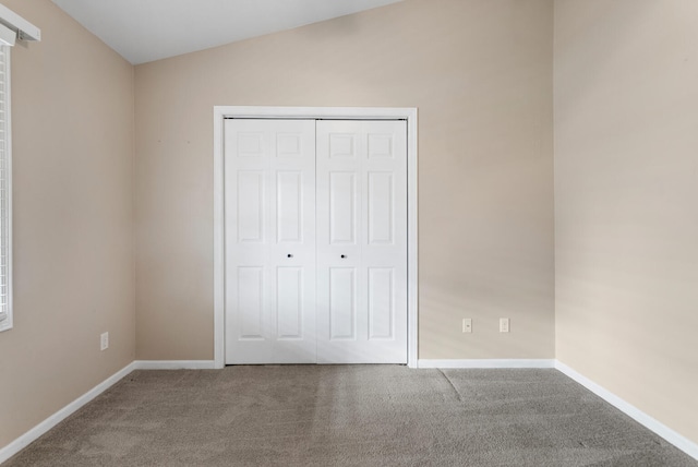 unfurnished bedroom featuring carpet, vaulted ceiling, and a closet