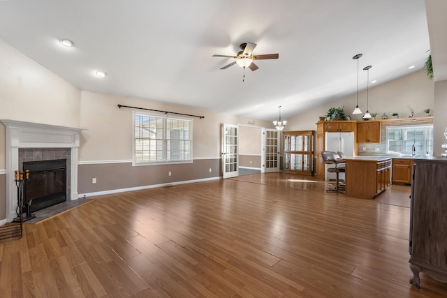 unfurnished living room featuring lofted ceiling, ceiling fan, dark wood-type flooring, and a tiled fireplace