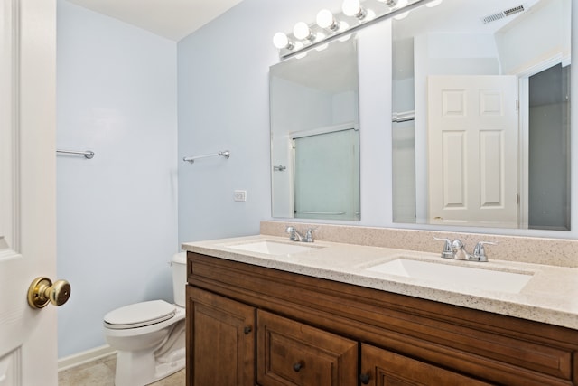 bathroom featuring tile patterned flooring, a shower with door, vanity, and toilet