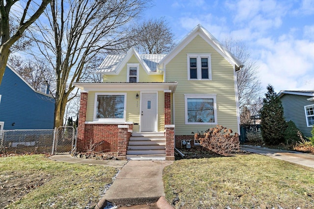 traditional-style house featuring a front yard, a gate, brick siding, and fence