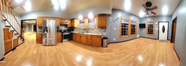 kitchen featuring appliances with stainless steel finishes, tasteful backsplash, vaulted ceiling, ceiling fan, and light hardwood / wood-style flooring