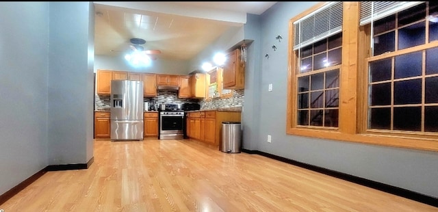 kitchen with ceiling fan, light stone countertops, stainless steel appliances, backsplash, and light hardwood / wood-style floors