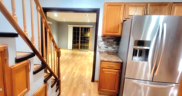 kitchen with light hardwood / wood-style flooring, light stone countertops, stainless steel refrigerator with ice dispenser, and tasteful backsplash