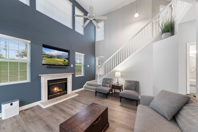 living room featuring hardwood / wood-style floors, a towering ceiling, ceiling fan, and plenty of natural light