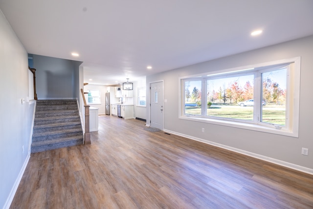 unfurnished living room with dark wood-type flooring, sink, and a notable chandelier