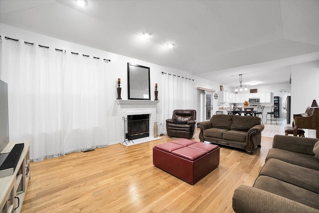 living room with light wood-type flooring, lofted ceiling, and a notable chandelier