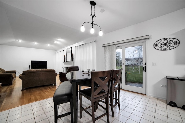 dining area featuring light hardwood / wood-style flooring, vaulted ceiling, and an inviting chandelier