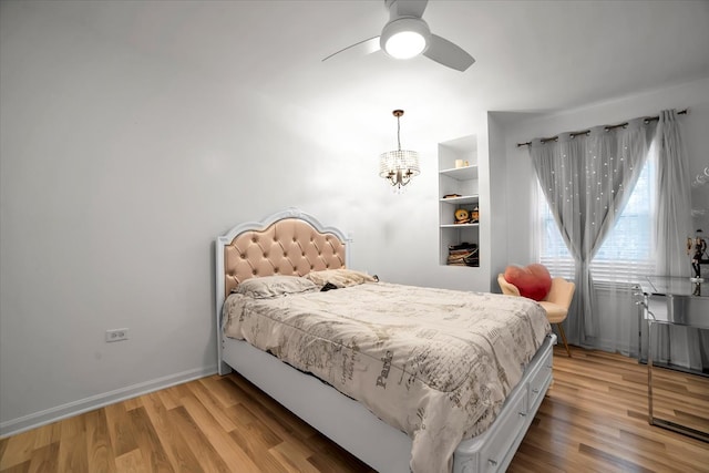 bedroom with ceiling fan with notable chandelier and light hardwood / wood-style flooring