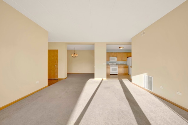 spare room featuring light carpet and a notable chandelier