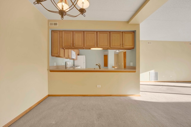 kitchen with kitchen peninsula, a chandelier, light carpet, sink, and white appliances