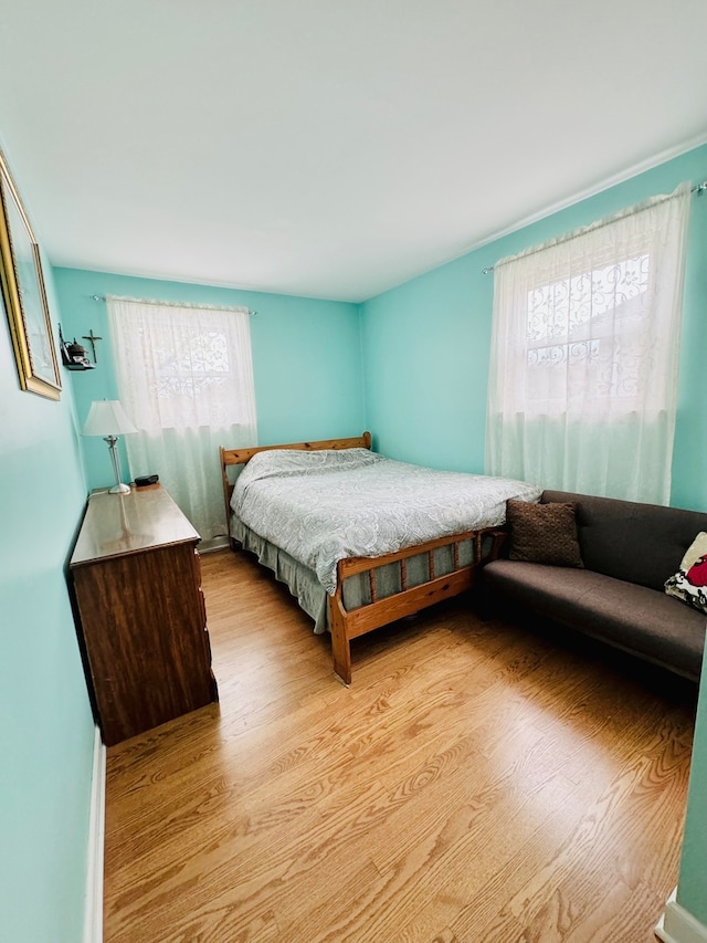 bedroom with multiple windows and light hardwood / wood-style flooring