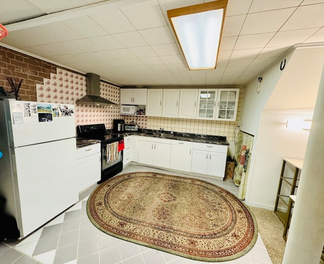 kitchen featuring light tile patterned floors, sink, white cabinets, white appliances, and wall chimney exhaust hood